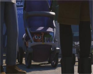 An animated scene from the Pixar film "Finding Dory." An image of a outdoor crowd with a baby stroller with an octopus and a sippy cup with a blue fish inside.